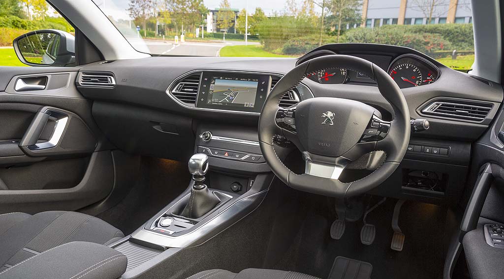 Peugeot 308 interior shot showing the large touchscreen and high mounted instrument panel. The steering wheel is smaller than you'd expect.